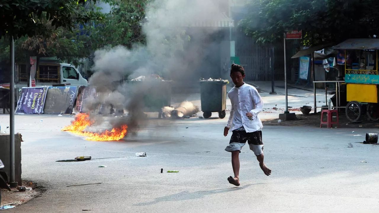 Un homme traverse la rue près d'une barricade en feu à Mandalay, en Birmanie, le 14 mars 2021 © AP