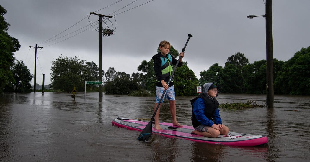 Deux adolescents pagayant à travers les rues inondées de Windsor, en Australie, lundi 22 mars © Matthew Abbott/The New York Times