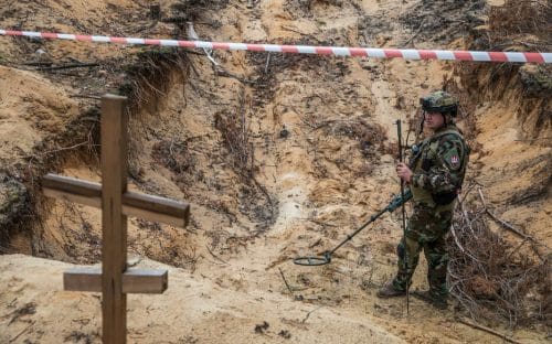 Un militaire ukrainien utilise un détecteur de métaux pour inspecter la fosse commune découverte sur un site d'un cimetière improvisé de civils et de soldats ukrainiens à Izioum, jeudi 15 septembre 2022 . © Oleksandr Khomenko / Reuters