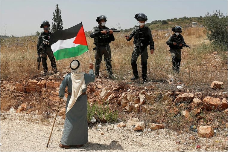 Un manifestant brandit un drapeau palestinien devant les forces israéliennes