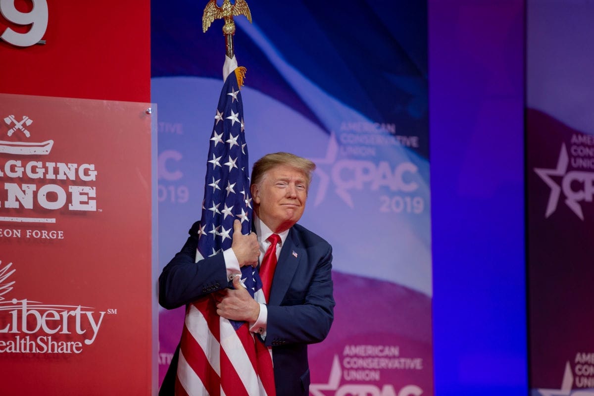 Le président Donald Trump enlace le drapeau américain